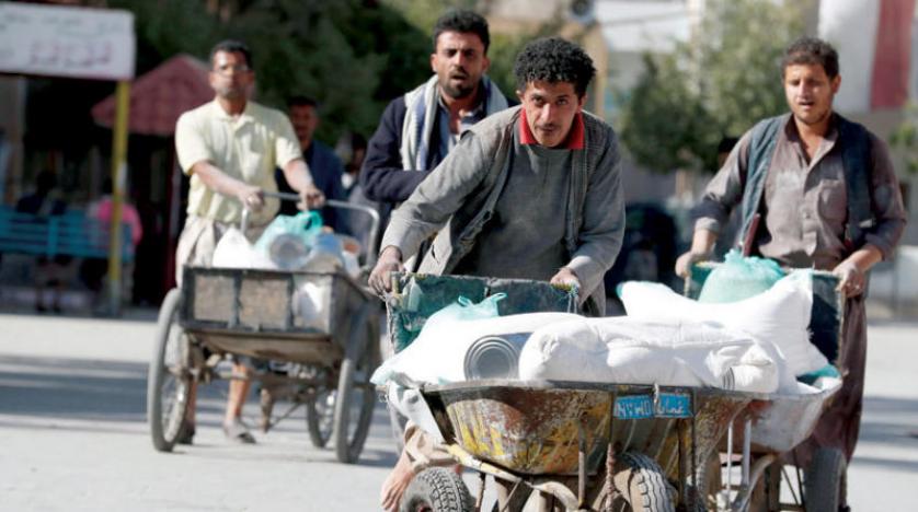 يمنيون يدفعون عربات تحمل دقيقاً تابعاً لبرنامج الغذاء العالمي في صنعاء (إ.ب.أ)